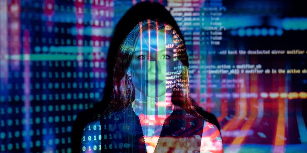 Portrait of a woman with code overlaid on her face from a projector.