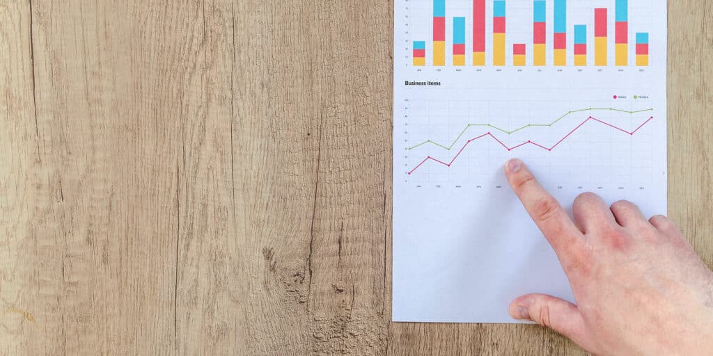 A person pointing at a line graph of annual business growth on a piece of paper.